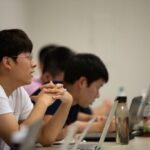 Students attentively listening and taking notes during a data science class, emphasizing active learning