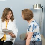 A female NP reviews a document with a female patient in an exam room