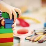 Child playing with colorful blocks, representing early childhood development and learning through play.