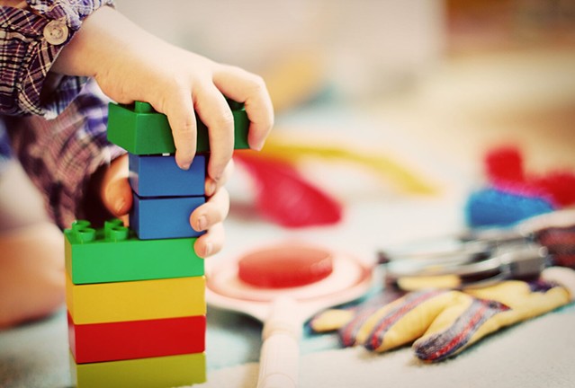 Child playing with colorful blocks, representing early childhood development and learning through play.