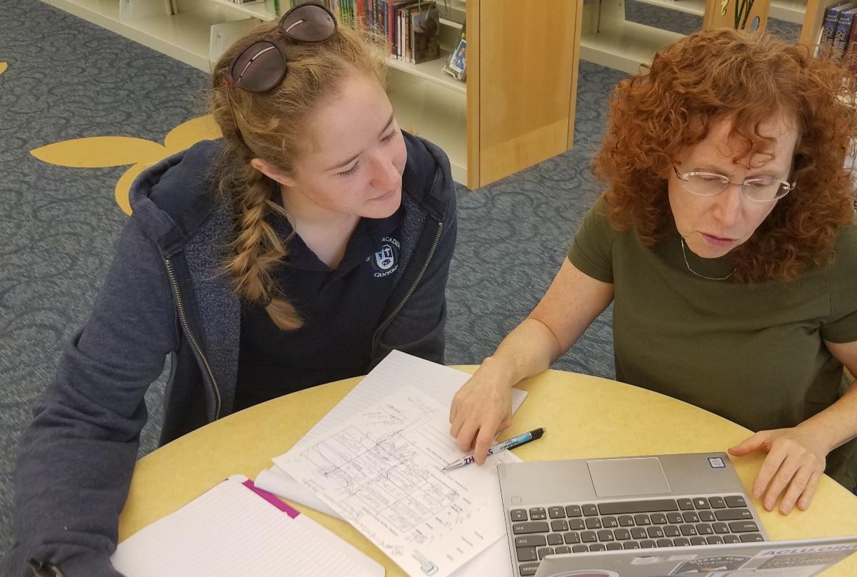 A close-up image of a student intently focused on a tablet, possibly researching or working on coursework during a summer college program, emphasizing academic focus.