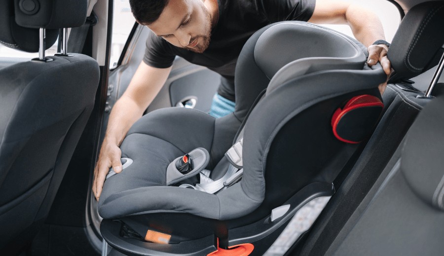 A parent carefully installing a car seat in their vehicle, ensuring it is securely fastened.