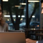 Woman in glasses smiles and points at laptop screen during a career counseling session.