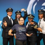 Five women pilots and representatives from Alaska Airlines and Sisters of the Skies pose for a photo, highlighting the partnership to promote diversity in aviation careers.