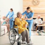 Nurse Giving Glass Of Water To Elderly Woman In Wheelchair At Retirement Home. A compassionate nurse aids a senior woman in a wheelchair at a retirement home, illustrating aged care assessment program policy in practice.