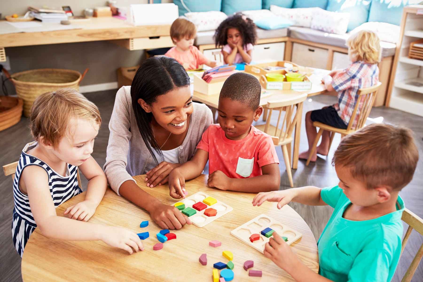 A preschool teacher assisting a child with learning activities.