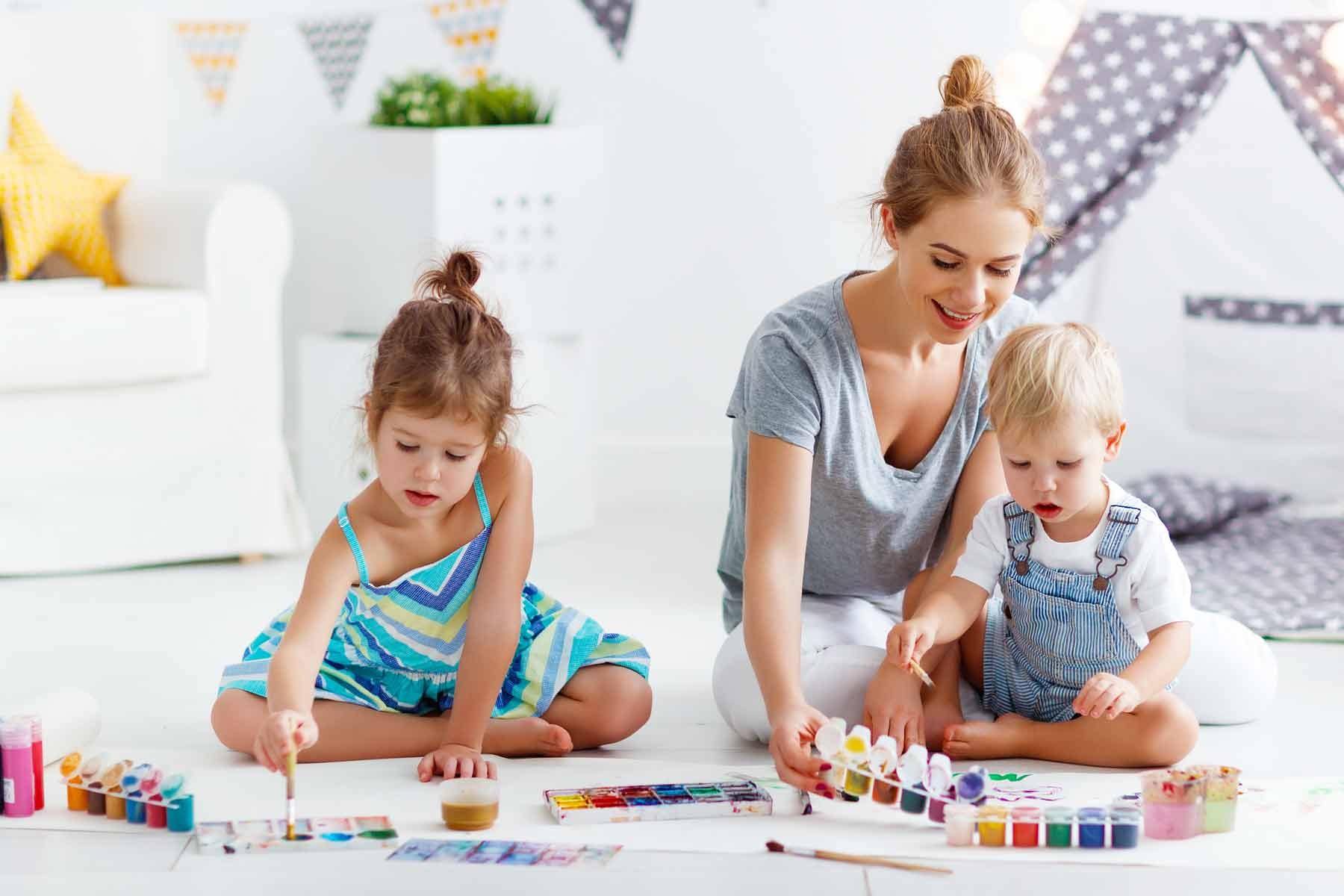 A babysitter and children participating in creative activities, showcasing babysitting as a potential, though often more expensive, after school care option compared to structured programs.