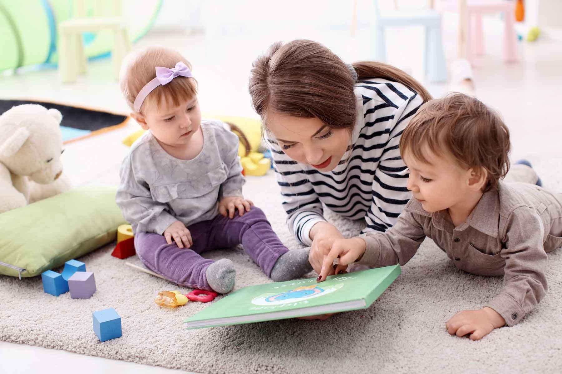 A nanny reading aloud to children in a cozy setting.