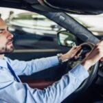 Man programming HomeLink buttons in car rearview mirror for garage door opener.